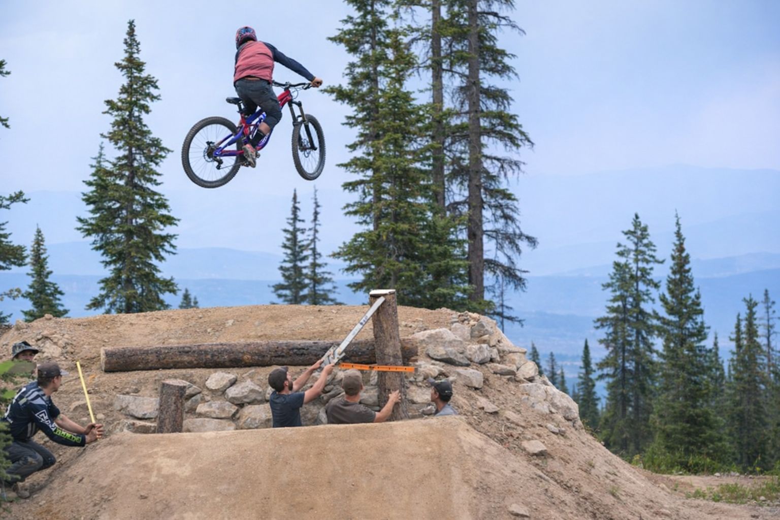 Mountainbiker springt hoch über eine im Bau befindliche Rampe im Bikepark.